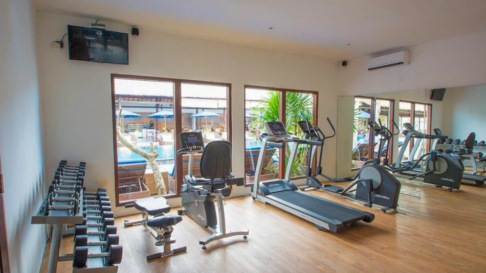 Modern gym at Lembongan Beach Club & Resort with cardio machines, weights, and pool views.