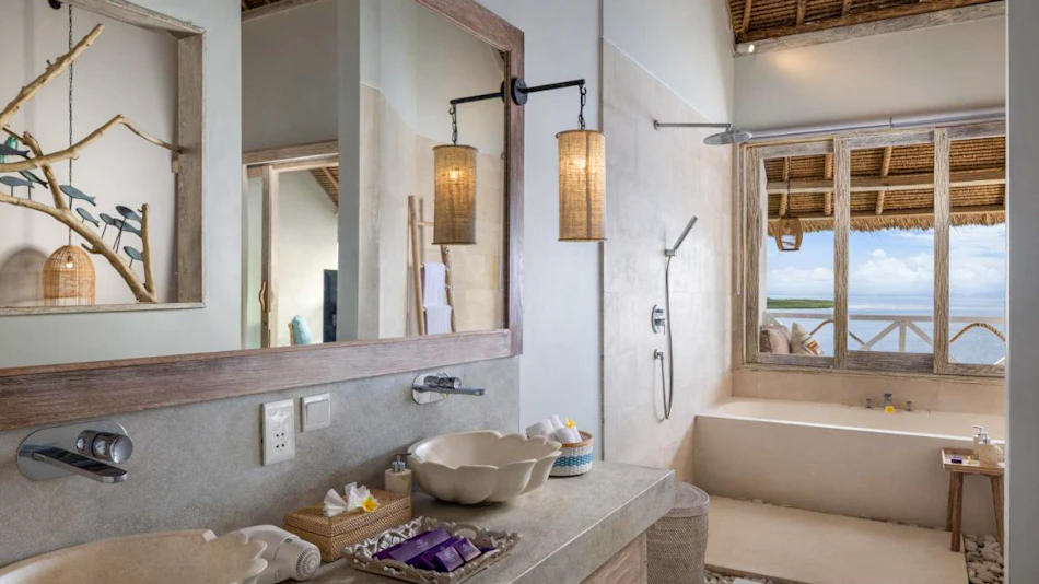 Serene bathroom with natural stone vanity, ocean view bathtub, and rustic thatched roof details.