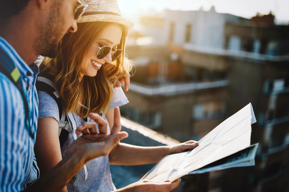 young couple reading a paper map at sunset