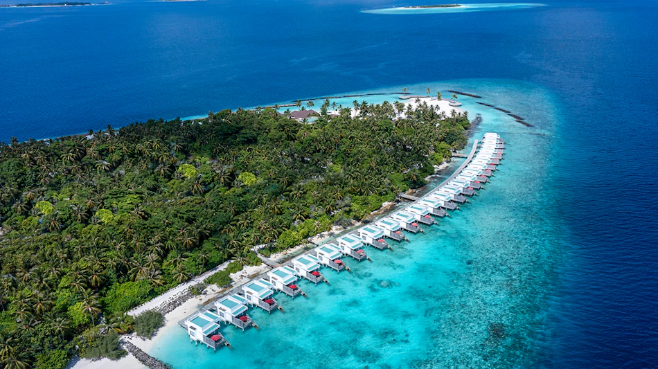 Aerial view of Dhigali Maldives resort with overwater villas extending into the turquoise ocean.