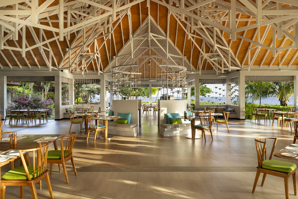 Bright, airy dining room at Dhigali Resort Maldives, featuring a high ceiling and ocean views.