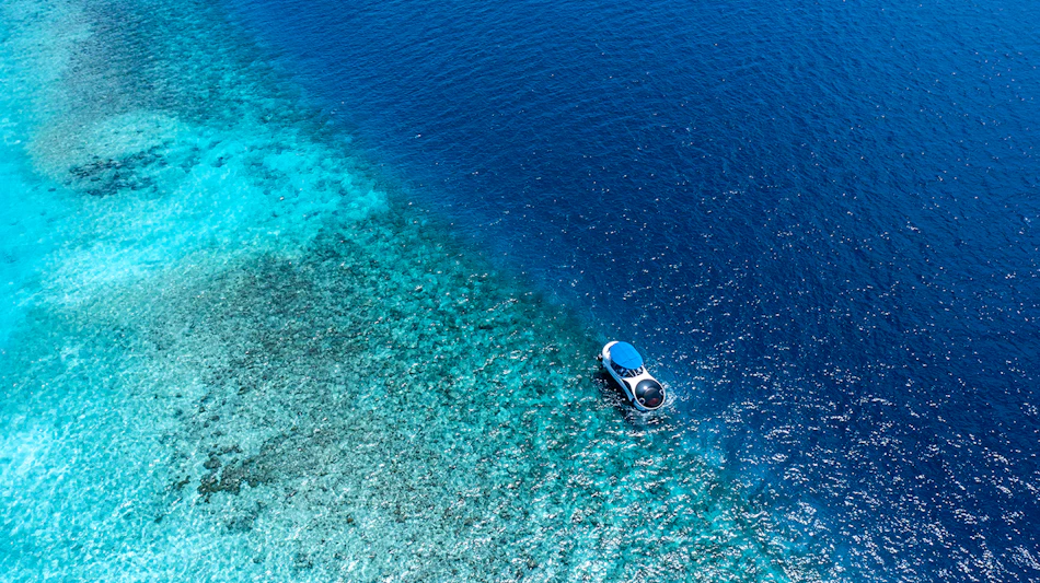 Aerial view of a semi-submersible boat exploring the clear turquoise waters of the Maldives.