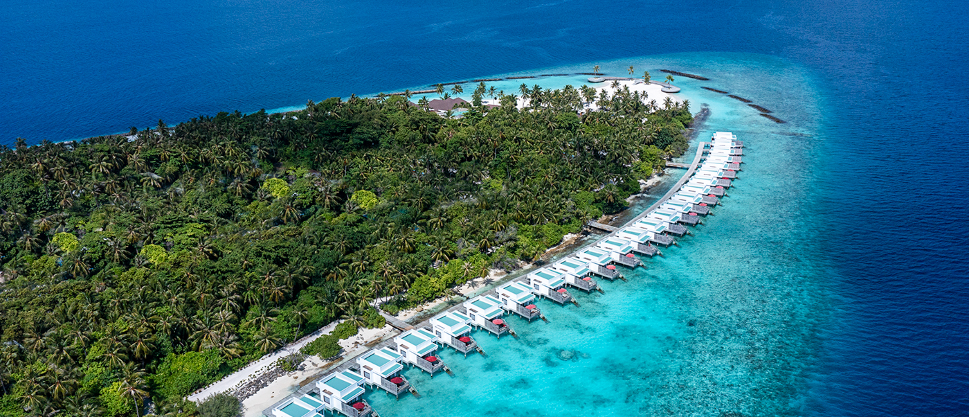Stunning aerial view of Dhigali Maldives resort with overwater villas and clear turquoise lagoon.