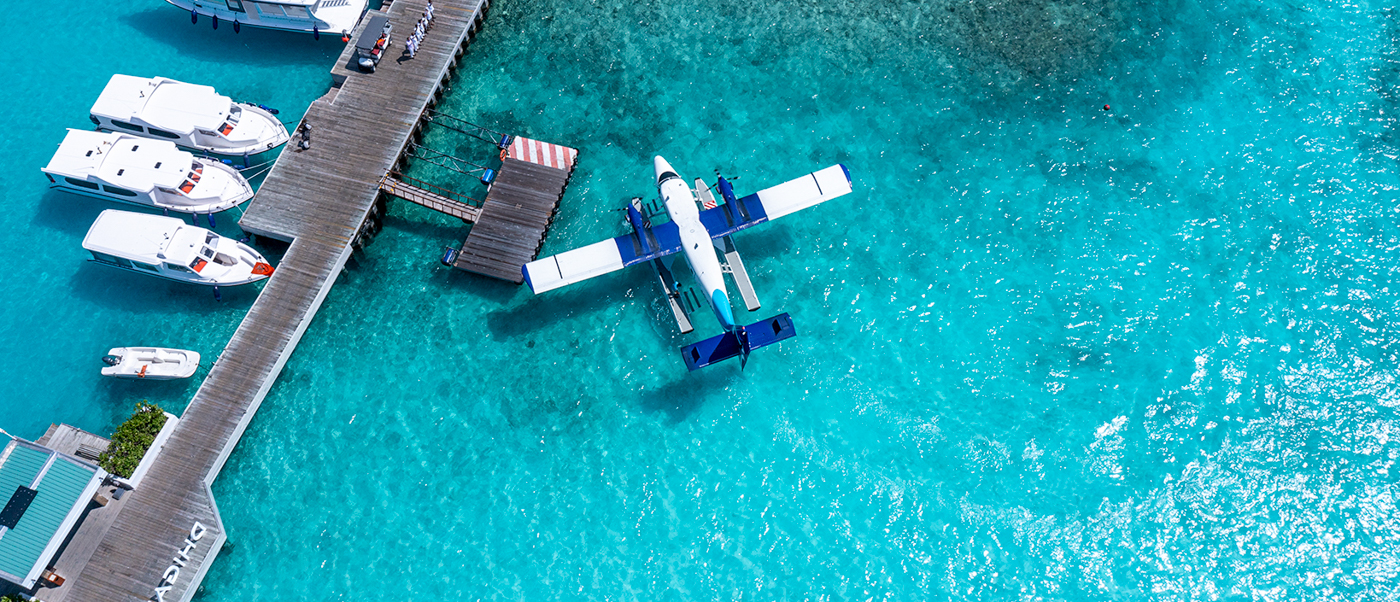 A seaplane docked at a pier with boats in the stunning turquoise waters of Dhigali Maldives.