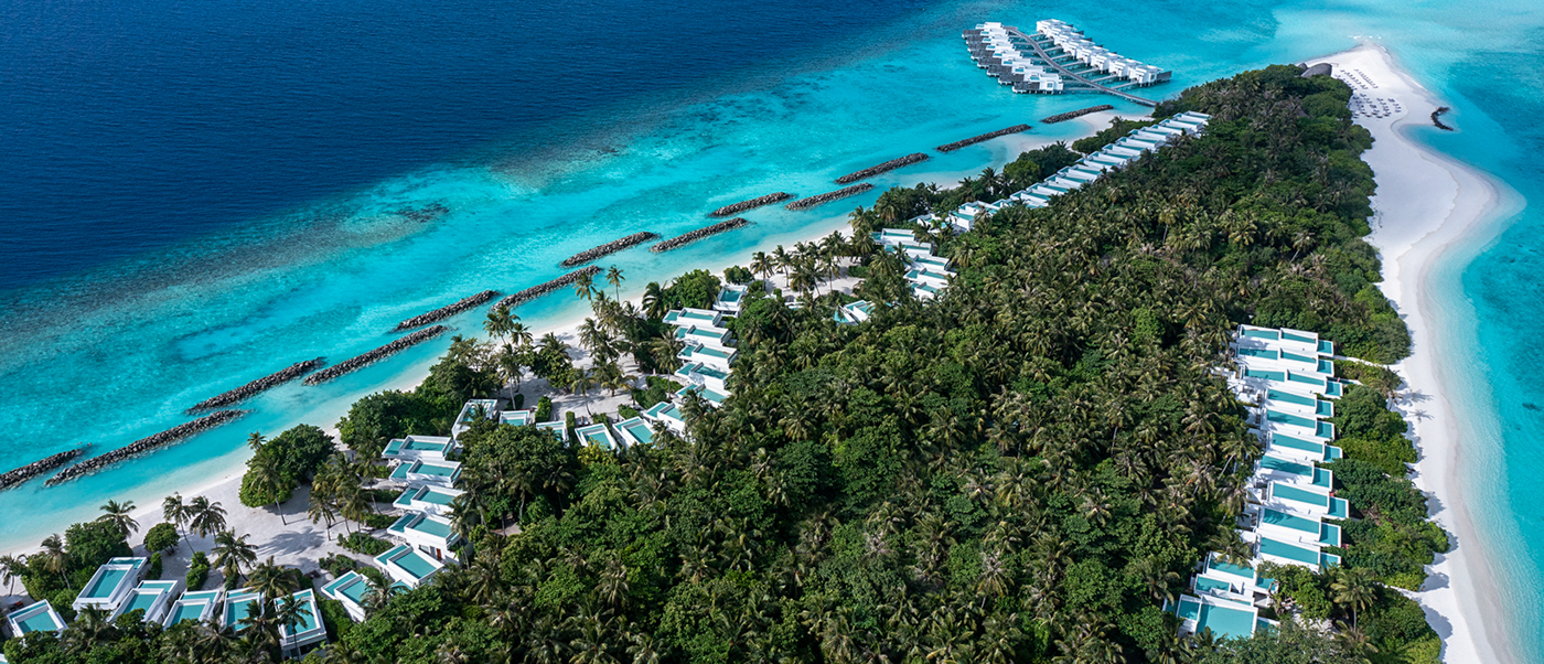 Aerial view of Dhigali Maldives resort, showcasing a lush island, white sand beaches, and luxury villas.