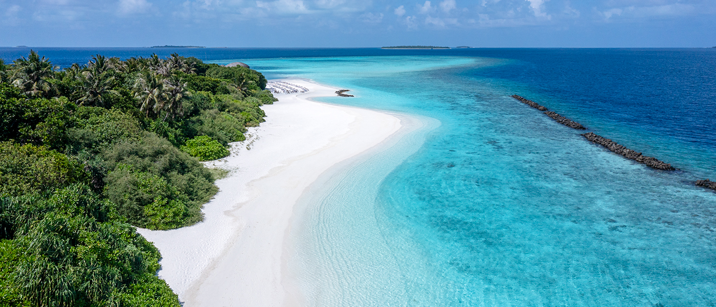 Dhigali Maldives island with a pristine white sand beach and clear turquoise ocean under blue sky.