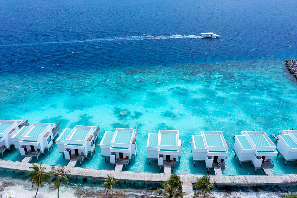 Luxurious overwater villas with private decks stretch into the clear turquoise waters of Dhigali Maldives.