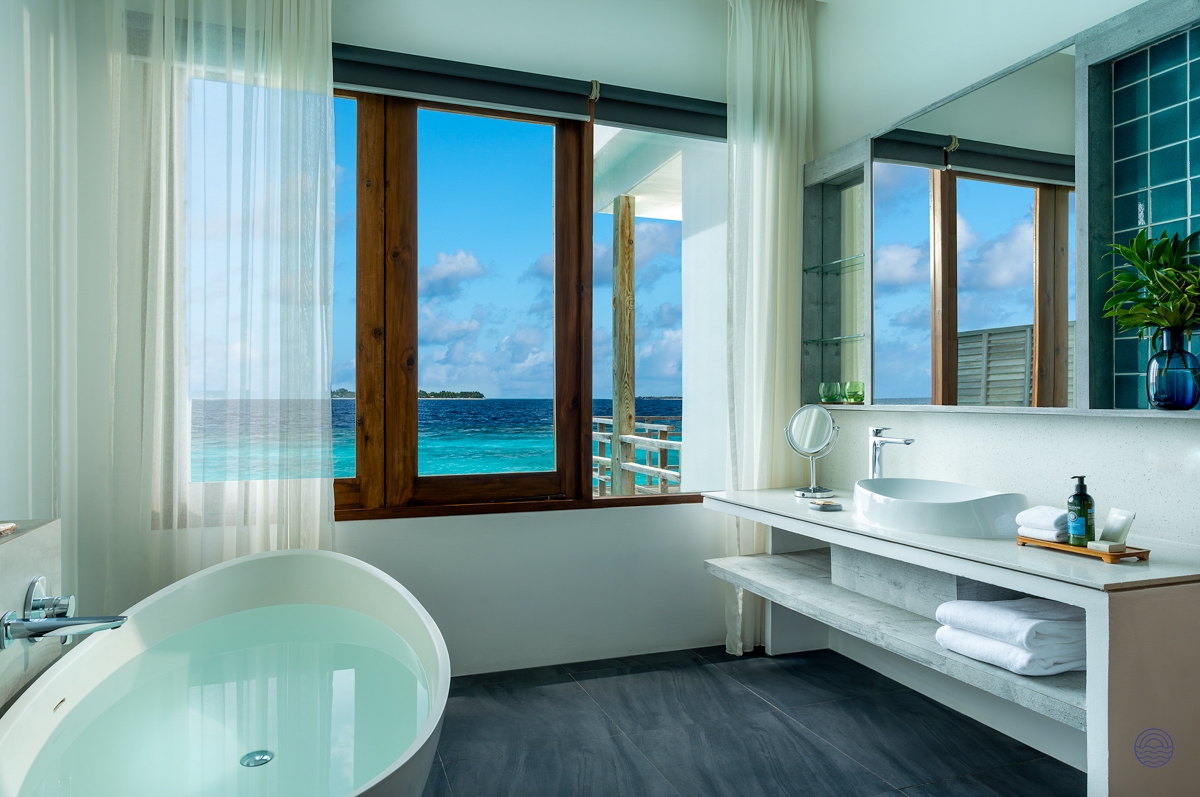 Luxurious bathroom in a Dhigali Maldives water villa, offering a freestanding tub and stunning ocean views.