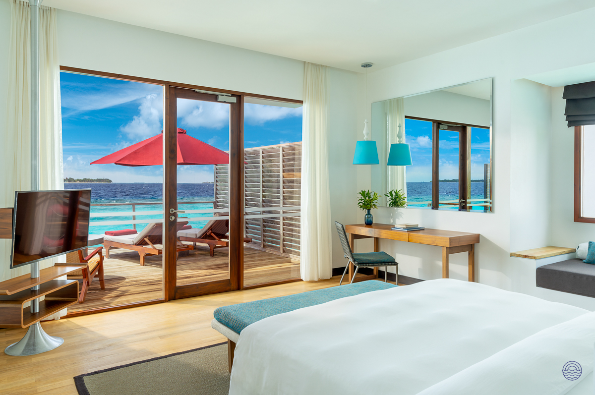 Spacious water villa bedroom at Dhigali Maldives with a private deck and stunning ocean views.