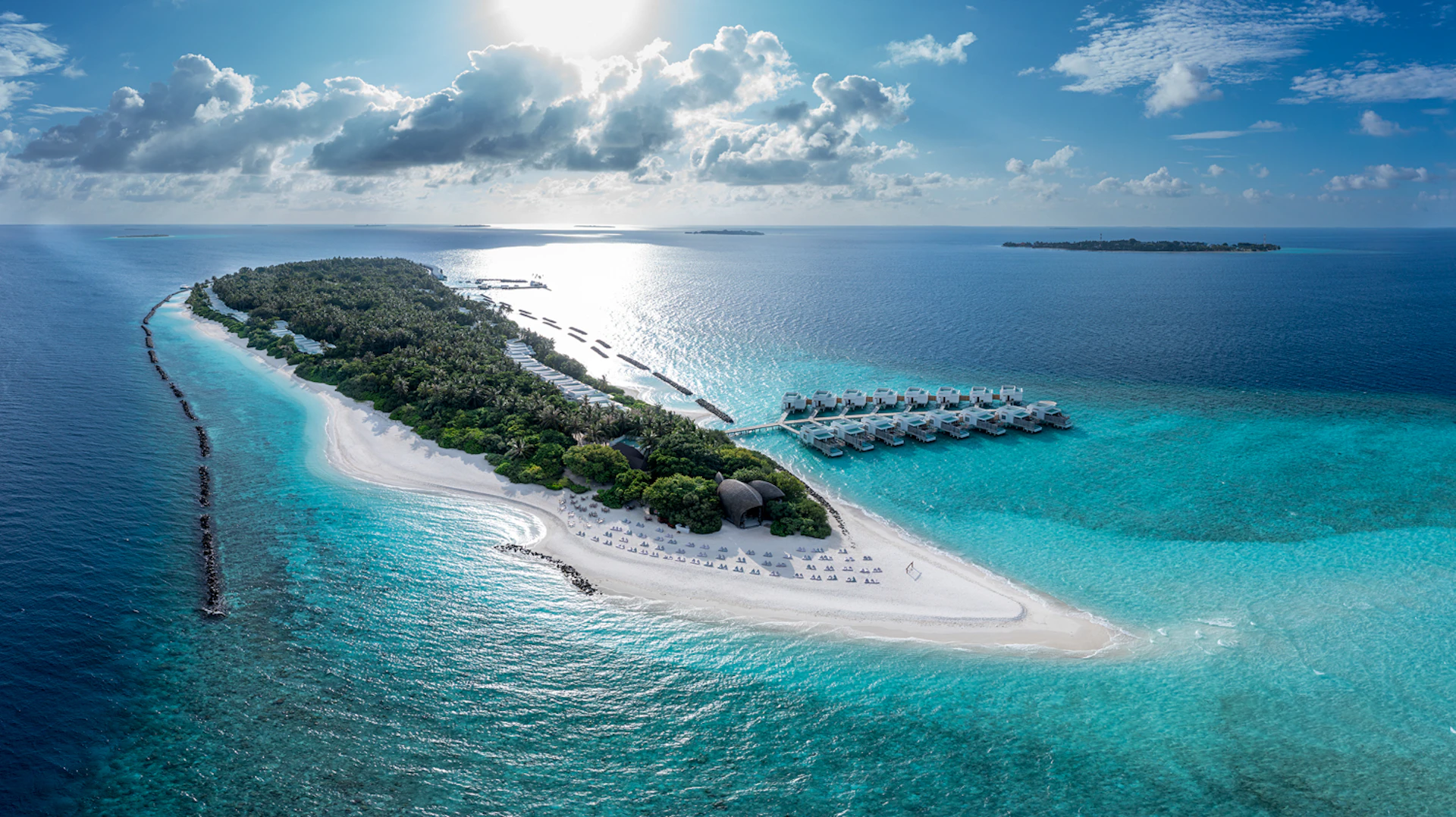 Aerial view of a beautiful tropical island with white sand beaches and luxury overwater villas in the Maldives.