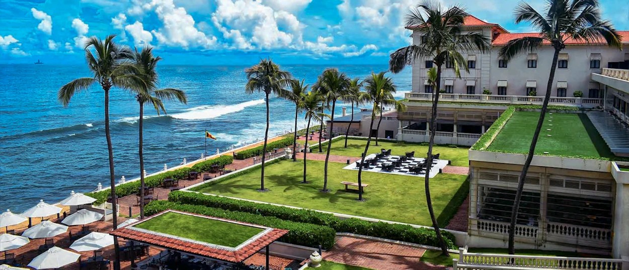 Elegant hotel with palm trees and green lawns overlooking the blue ocean in Colombo, Sri Lanka.