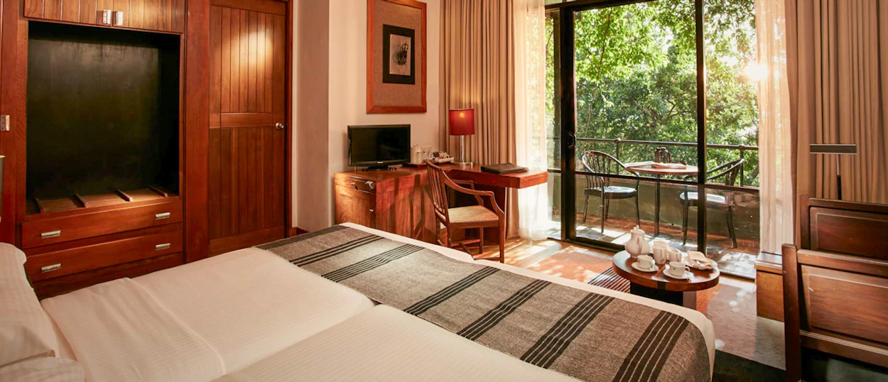 Elegant hotel room at Heritance Kandalama, Sigiriya, offering a serene balcony view of the forest.