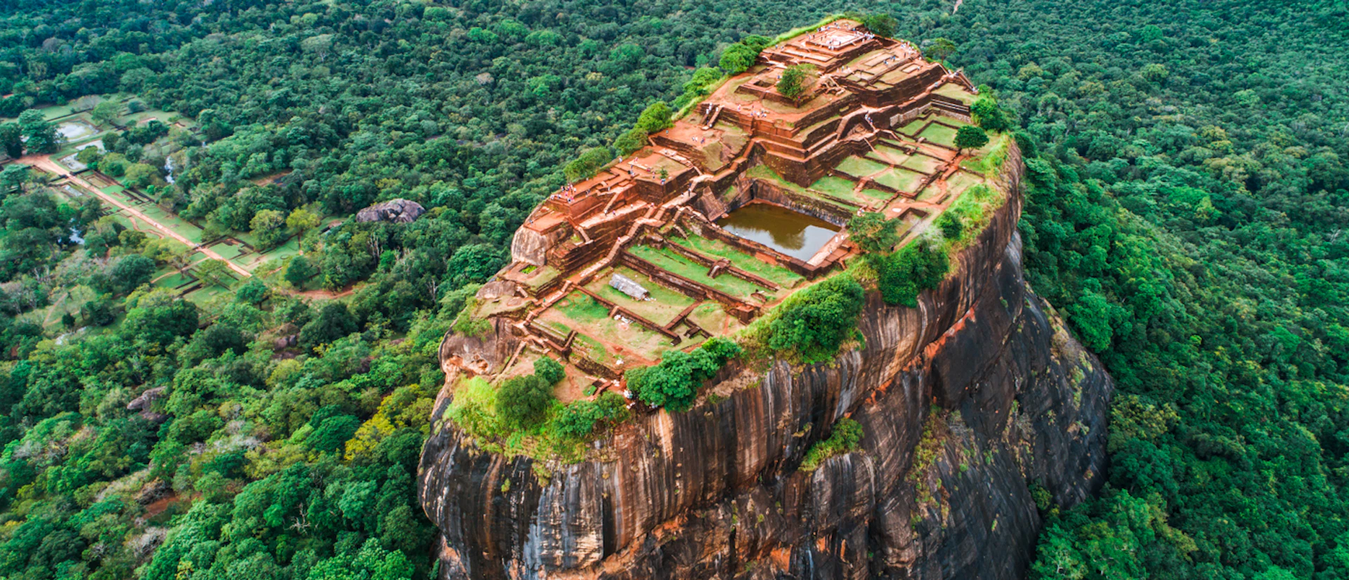 Aerial view of the ancient Sigiriya rock fortress in Sri Lanka, surrounded by dense green jungle.