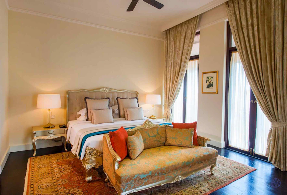 Elegant room at Galle Face Hotel Colombo, featuring a grand bed, ornate sofa, and large windows.