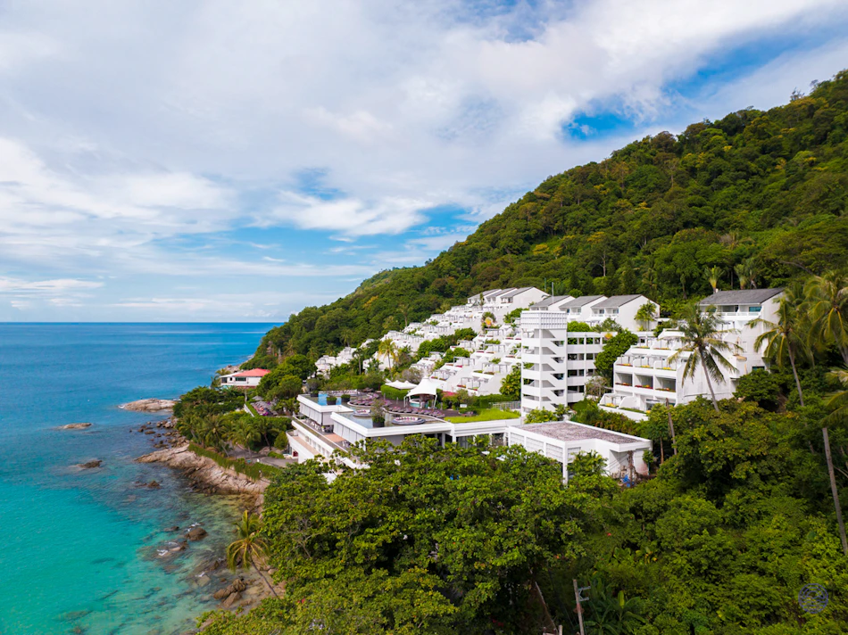 The Nai Harn resort's white buildings cascade down a lush green hillside to the turquoise sea in Phuket.
