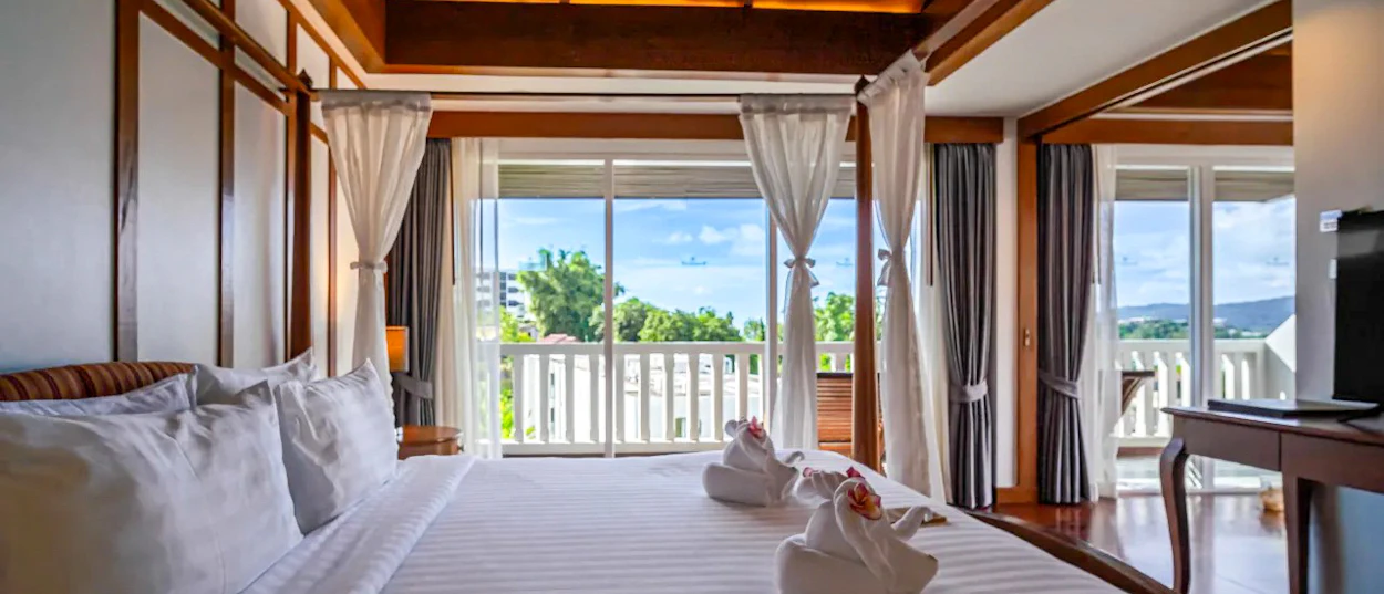 Bright resort room in Phuket with a large bed, towel swans, and a stunning ocean view.