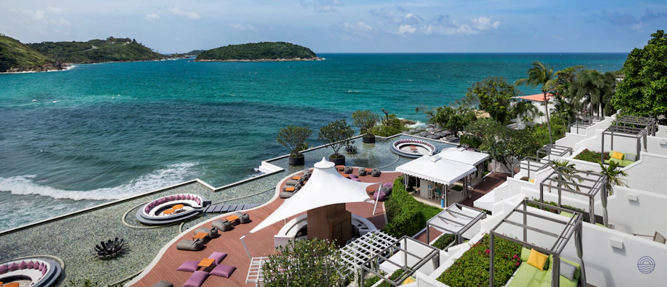 Luxury resort with terraced rooms and lounge areas overlooking the turquoise Andaman Sea in Phuket.