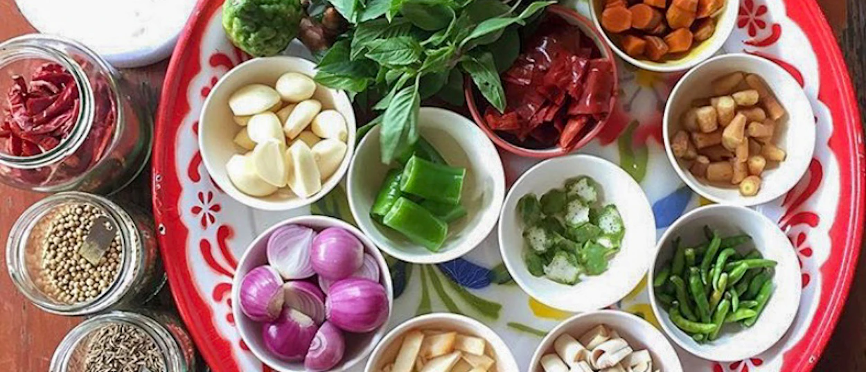 Colorful fresh Thai cooking ingredients, including garlic, shallots, and herbs, ready for a class in Chiang Mai.