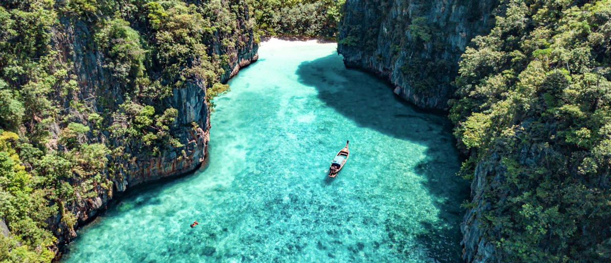 Aerial view of a longtail boat and swimmer in a beautiful turquoise bay in Koh Phi Phi.
