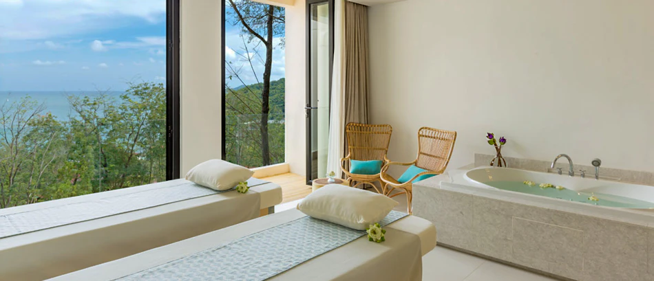 Luxurious spa room in Phuket with two massage beds, a large bathtub, and a stunning ocean view.