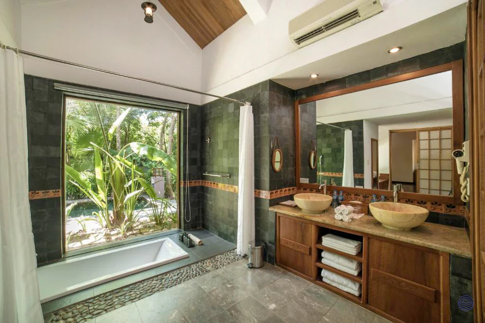 Luxurious resort bathroom in Hue, Vietnam, featuring a bathtub and tropical garden view.