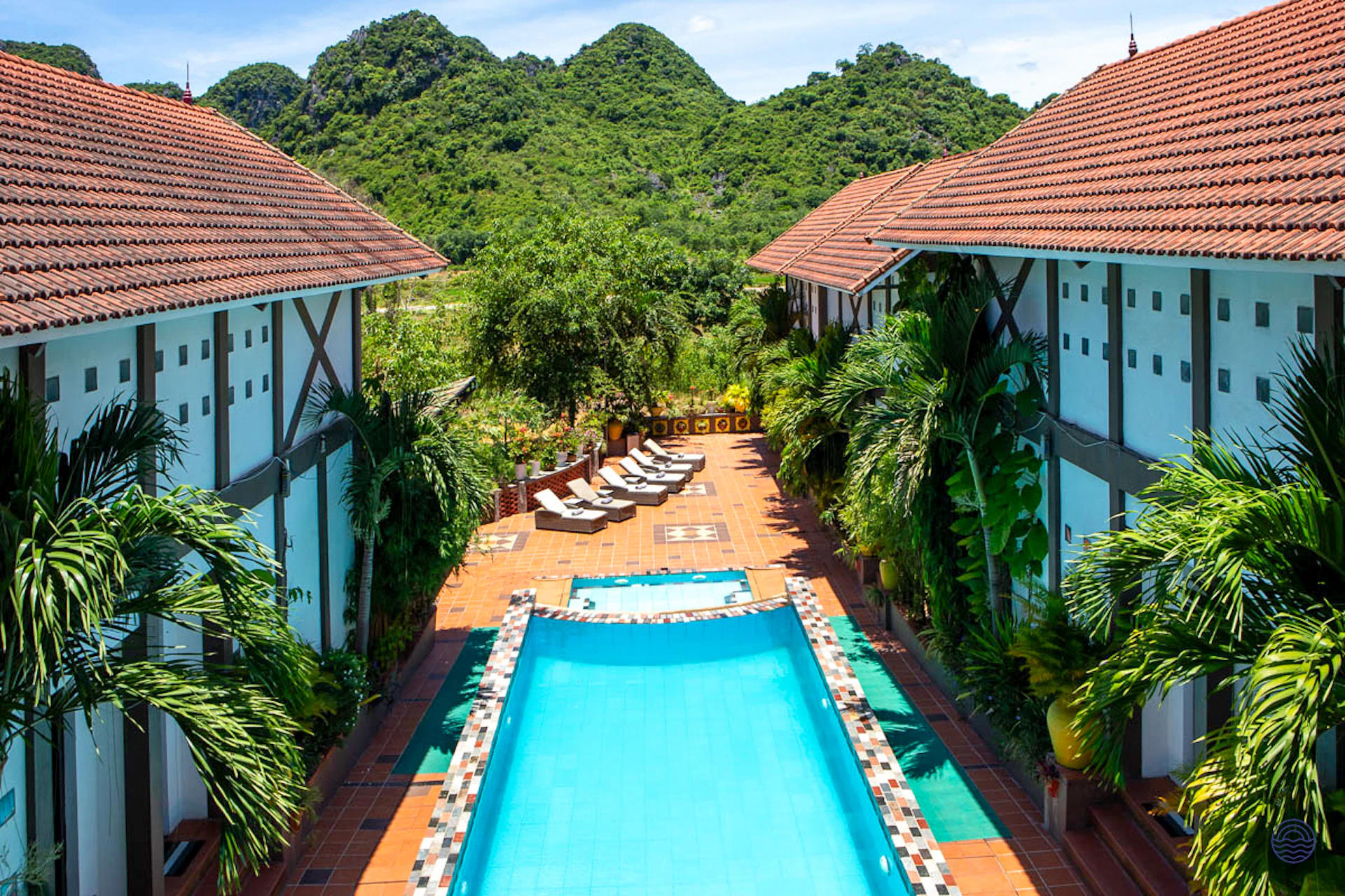 A tranquil swimming pool and lounge chairs at Victory Villas in Phong Nha, with green mountains.