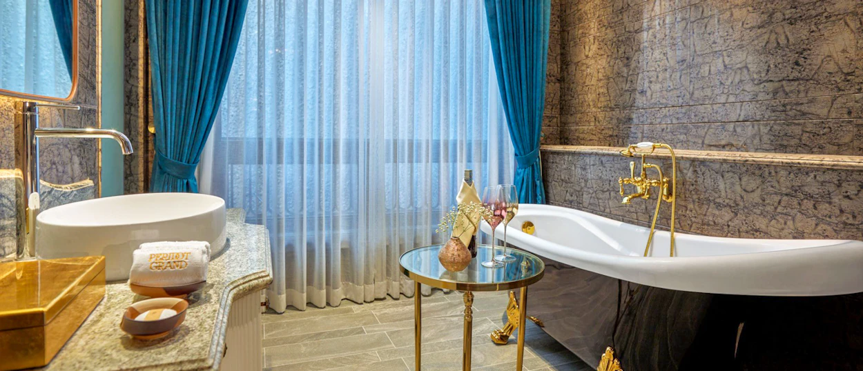Luxurious bathroom in Hanoi with a freestanding tub, gold fixtures, and champagne for a romantic honeymoon.