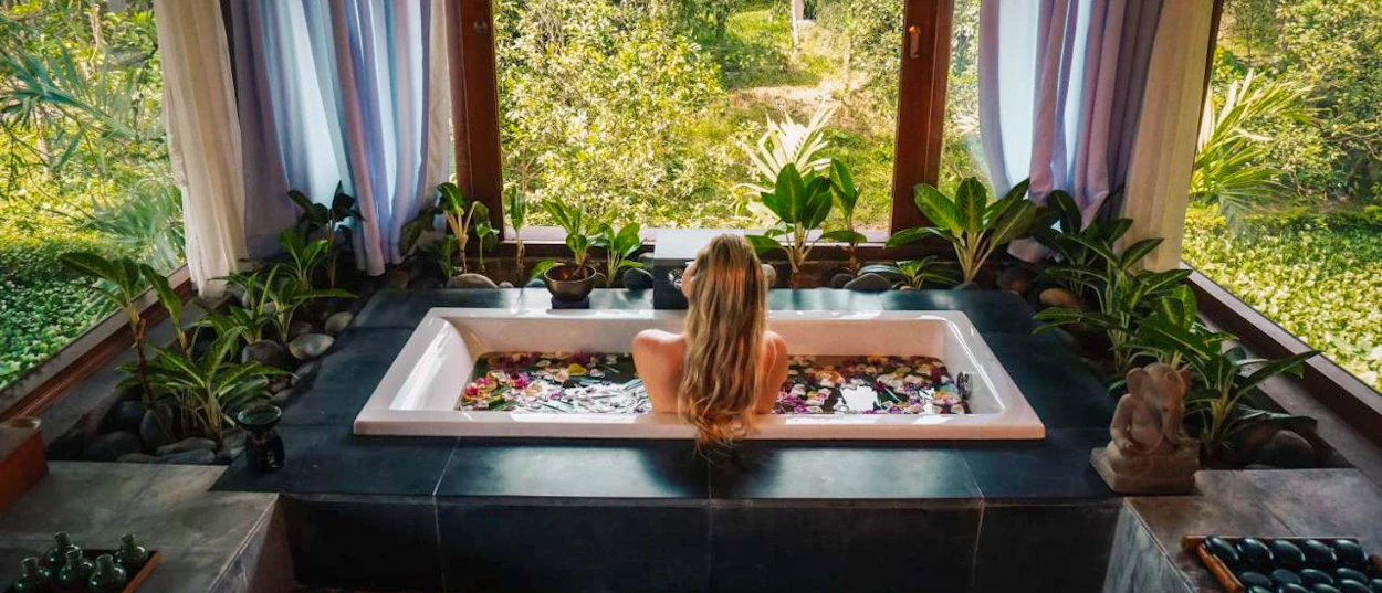 Blonde woman relaxes in a flower petal bath, enjoying the lush tropical garden view in Hue.