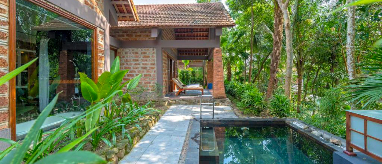 A tranquil private plunge pool and traditional hut nestled in a lush tropical garden in Hue.