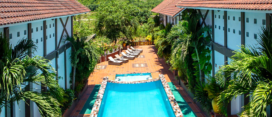 A tranquil resort swimming pool with sun loungers, flanked by villas and tropical plants in Vietnam.
