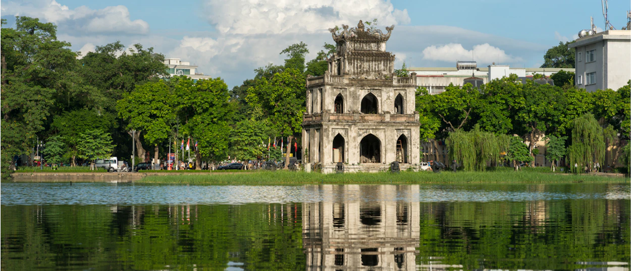 The ancient Turtle Tower on Hoan Kiem Lake in Hanoi, beautifully reflected in the serene water.