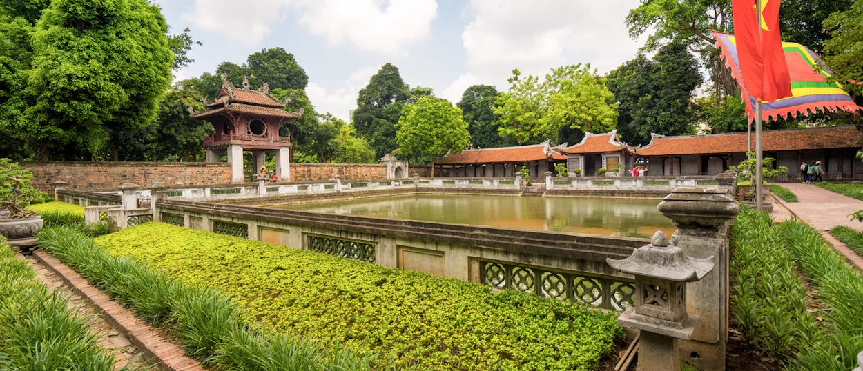 Historic Vietnamese temple complex in Hue featuring traditional buildings, a large pond, and lush greenery.