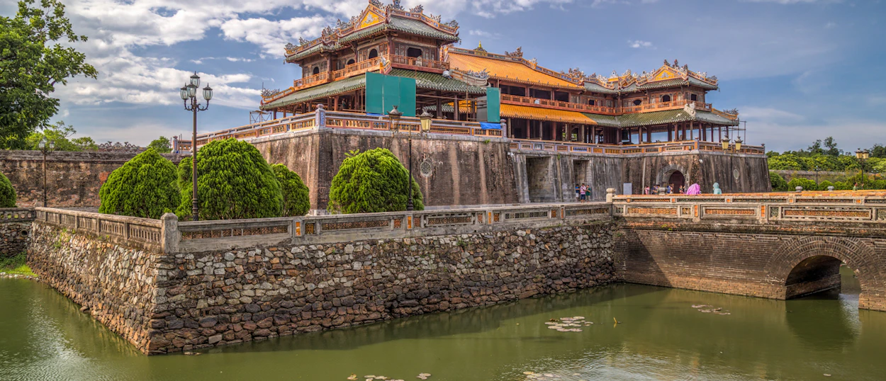 The grand Imperial Citadel in Hue, Vietnam, with its moat and ornate architecture under a blue sky.
